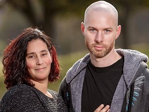 Brunette woman with black shirt standing next to bald man with black shirt and jacket.