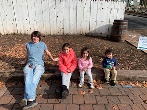 Children sitting on sidewalk with tallest on left and smallest on right. Boy girl girl boy order.